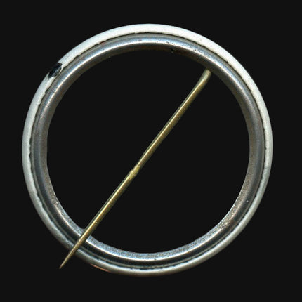 Metallic button with a central pin on a dark background